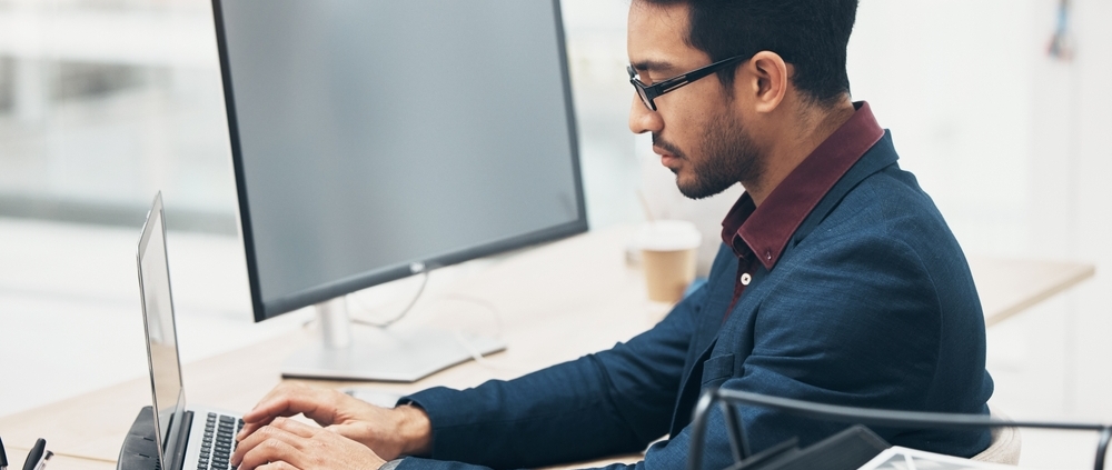 Financial executive working on a laptop in a modern office, preparing reports and forecasts as part of CFO services Kitchener businesses rely on for financial clarity.