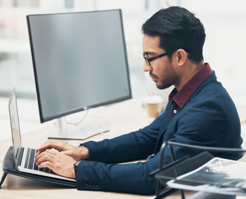 Financial executive working on a laptop in a modern office, preparing reports and forecasts as part of CFO services Kitchener businesses rely on for financial clarity.