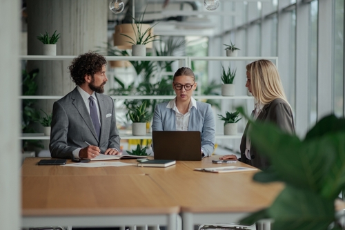 Three business professionals reviewing financial data on a laptop during a collaborative meeting as part of Fractional CFO Services.
