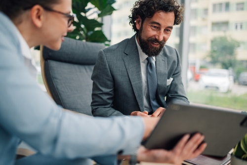 Part time CFO Services advisor reviewing financial reports on a tablet with a business owner during a one-on-one discussion.