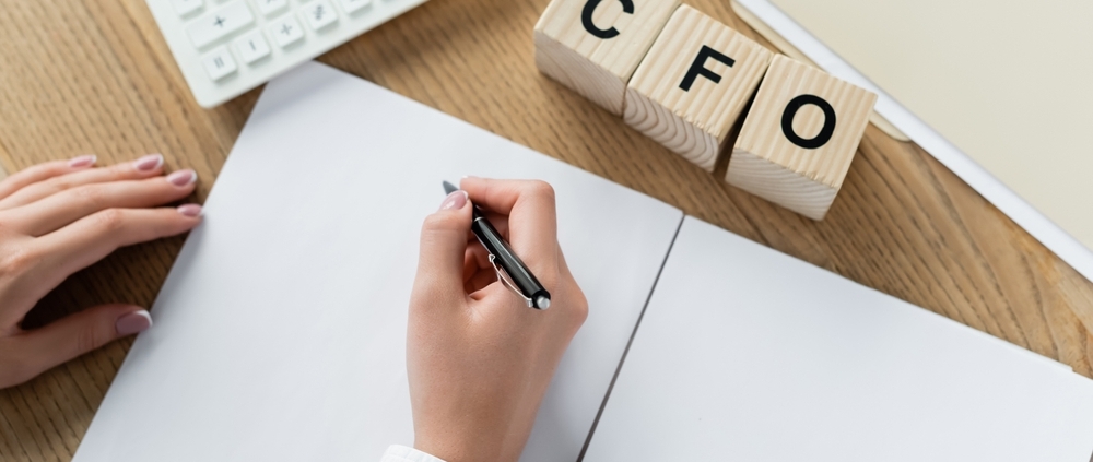 Business owner wondering when is it time to hire a CFO while reviewing financial reports at a desk in Guelph Ontario